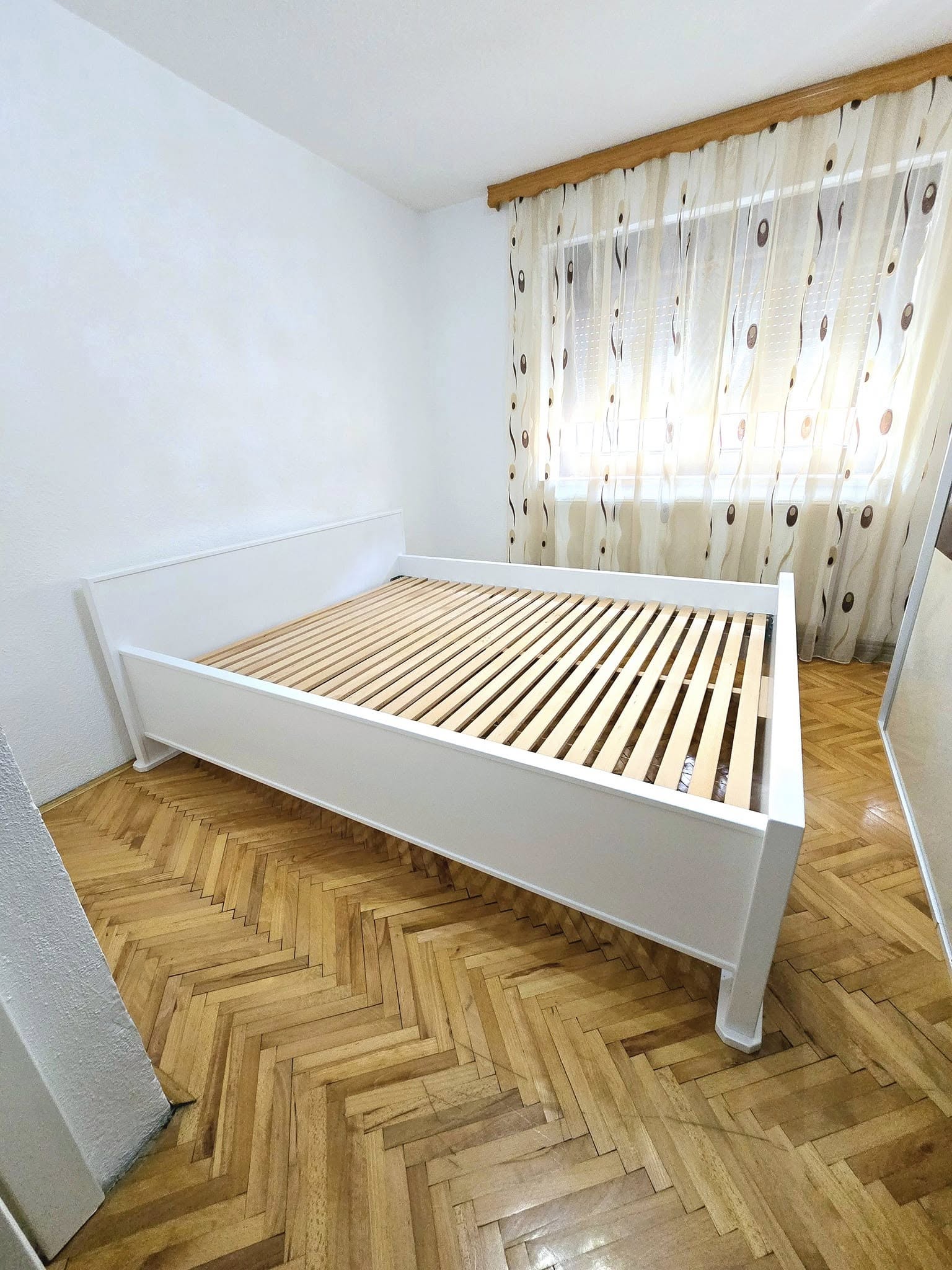 Bijeli bračni krevet s letvičastom podnicom, na ribljoj kosti